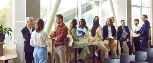 Groupe de professionnels diversifiés debout et discutant dans une salle de formation moderne et lumineuse
